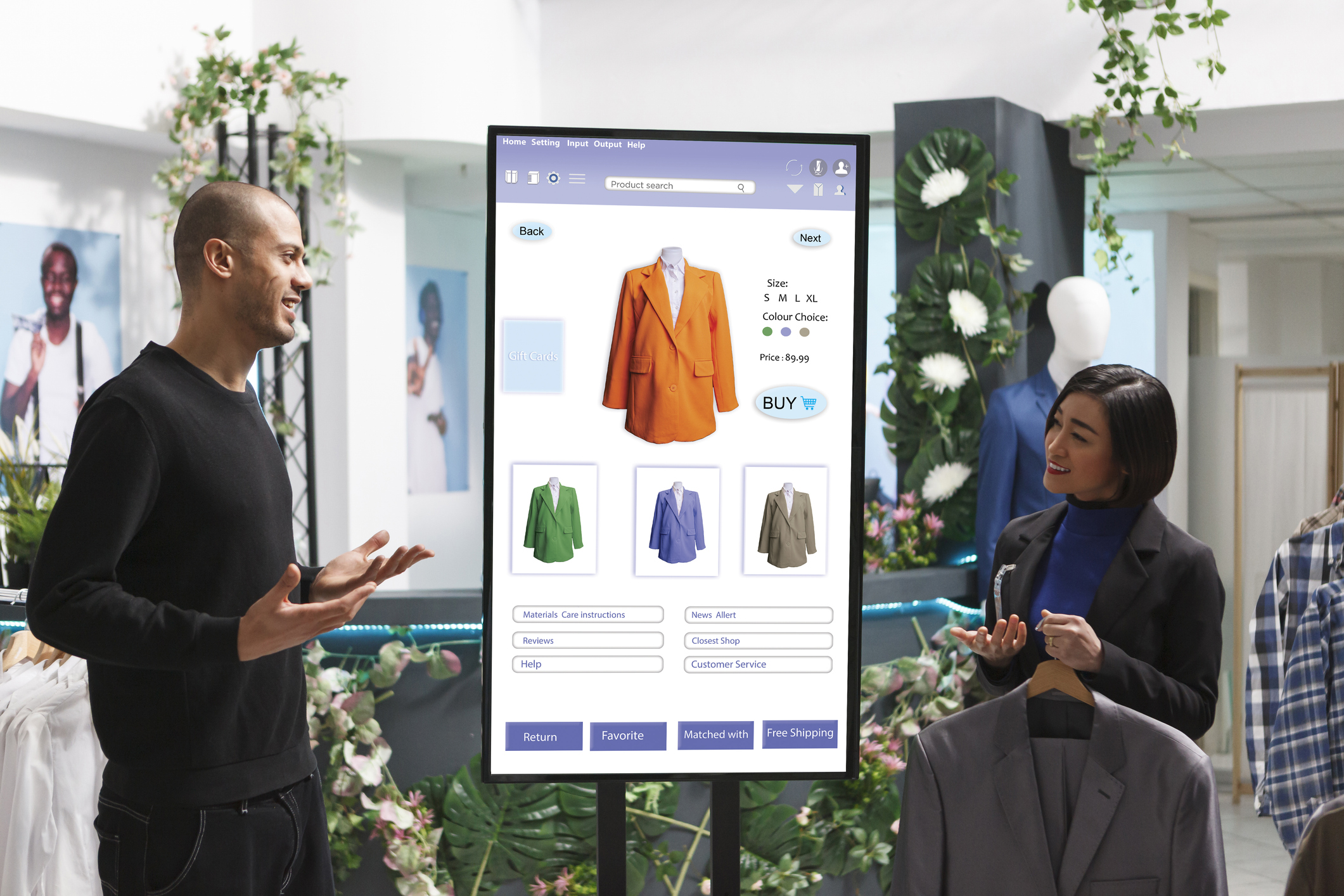 Store associate displays items to man in front of digital kiosk, selecting merchandise from clothing boutique. Caucasian male customer converses with female employee about products.