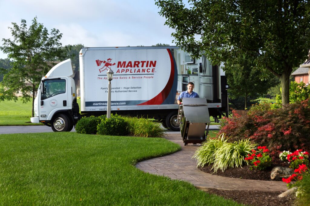 Appliance delivery truck with delivery driver pushing an oven on a dolly