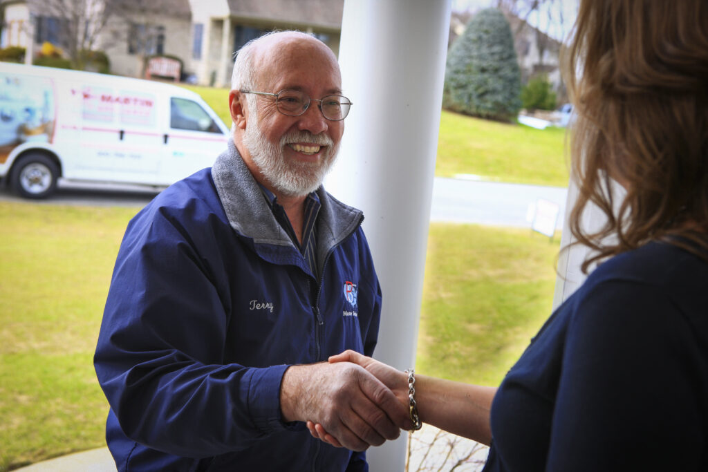 Service guy shaking woman's hand on the front porch