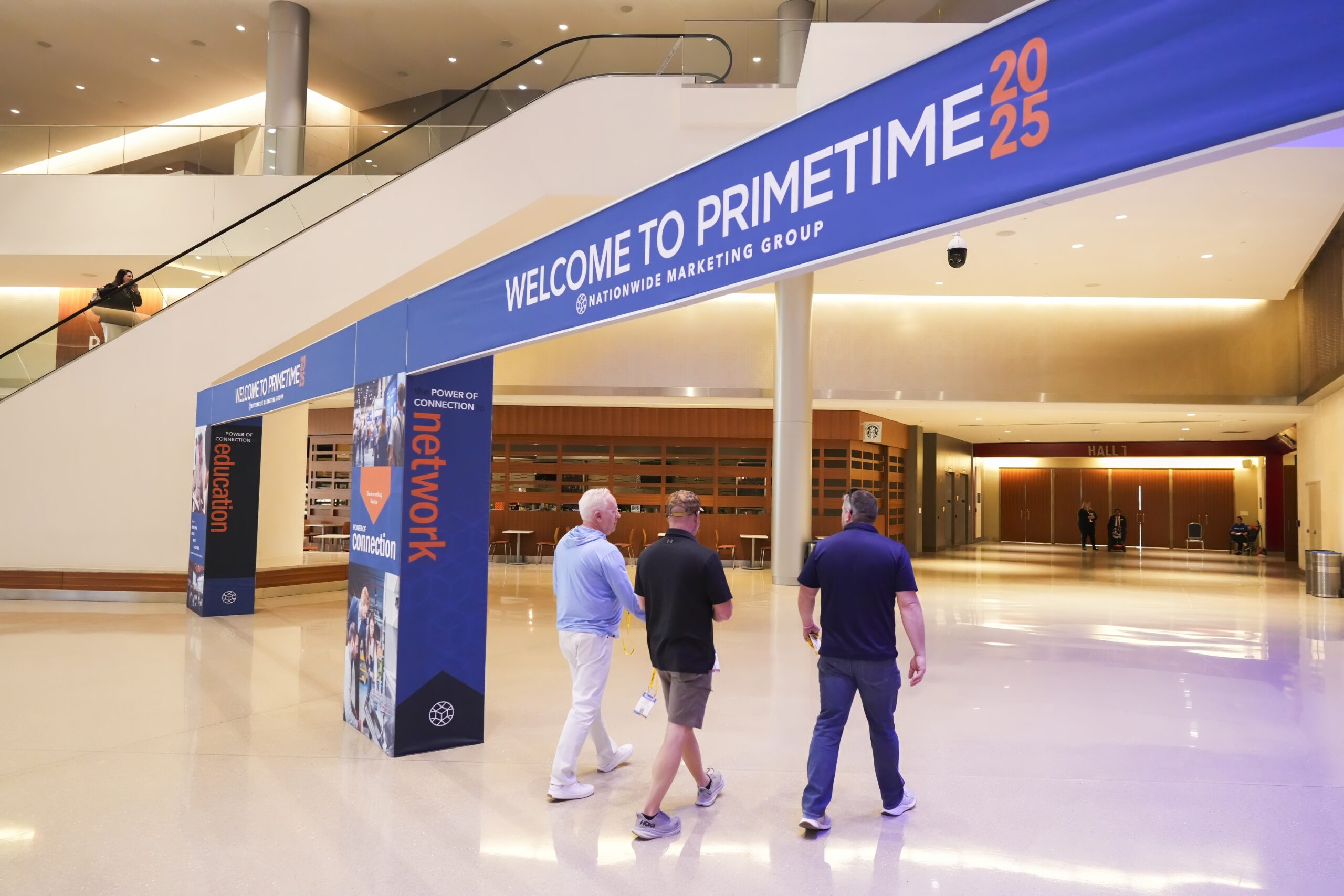 Three people walking under a banner sign