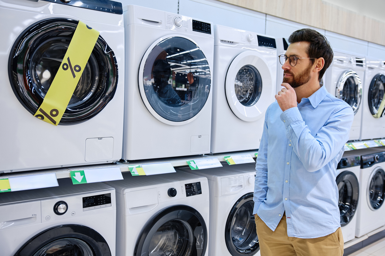 A Thoughtful Man Deeply Considering Various Washing Machines Available in Retail Store