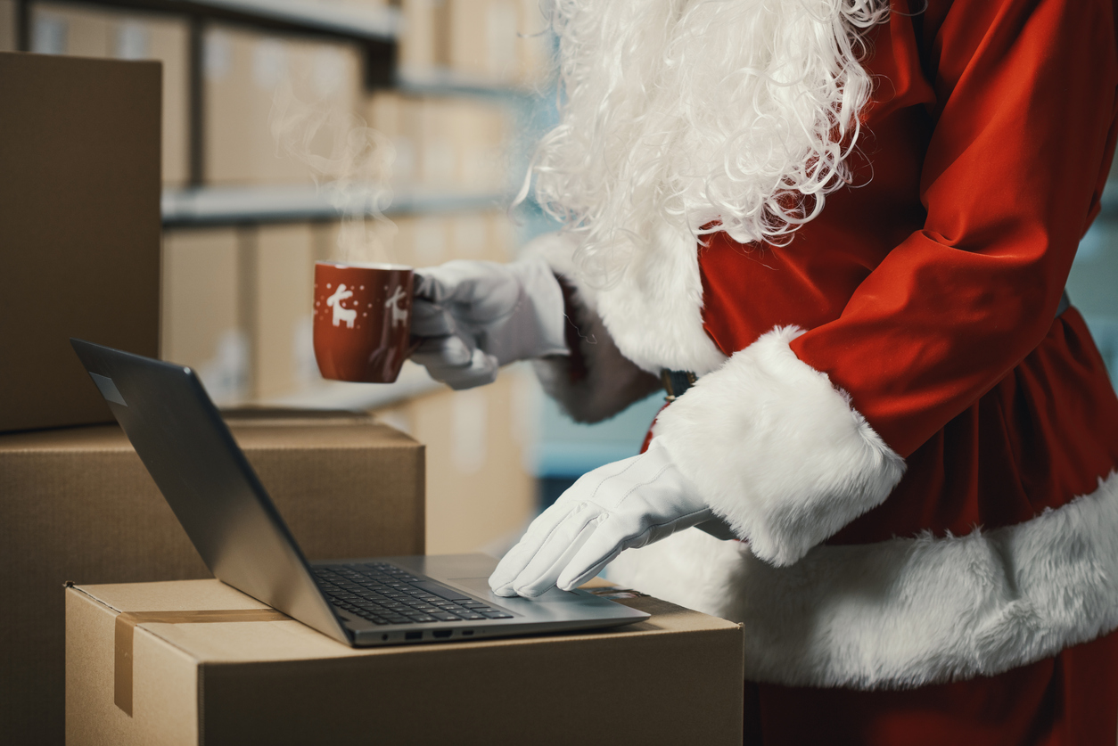 Santa Claus using a laptop in a warehouse