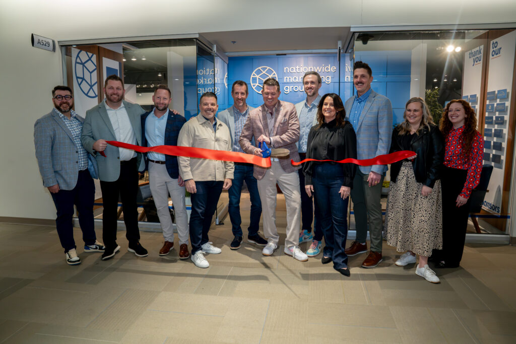Small group of people lined up to do a ribbon cutting in front of a showroom